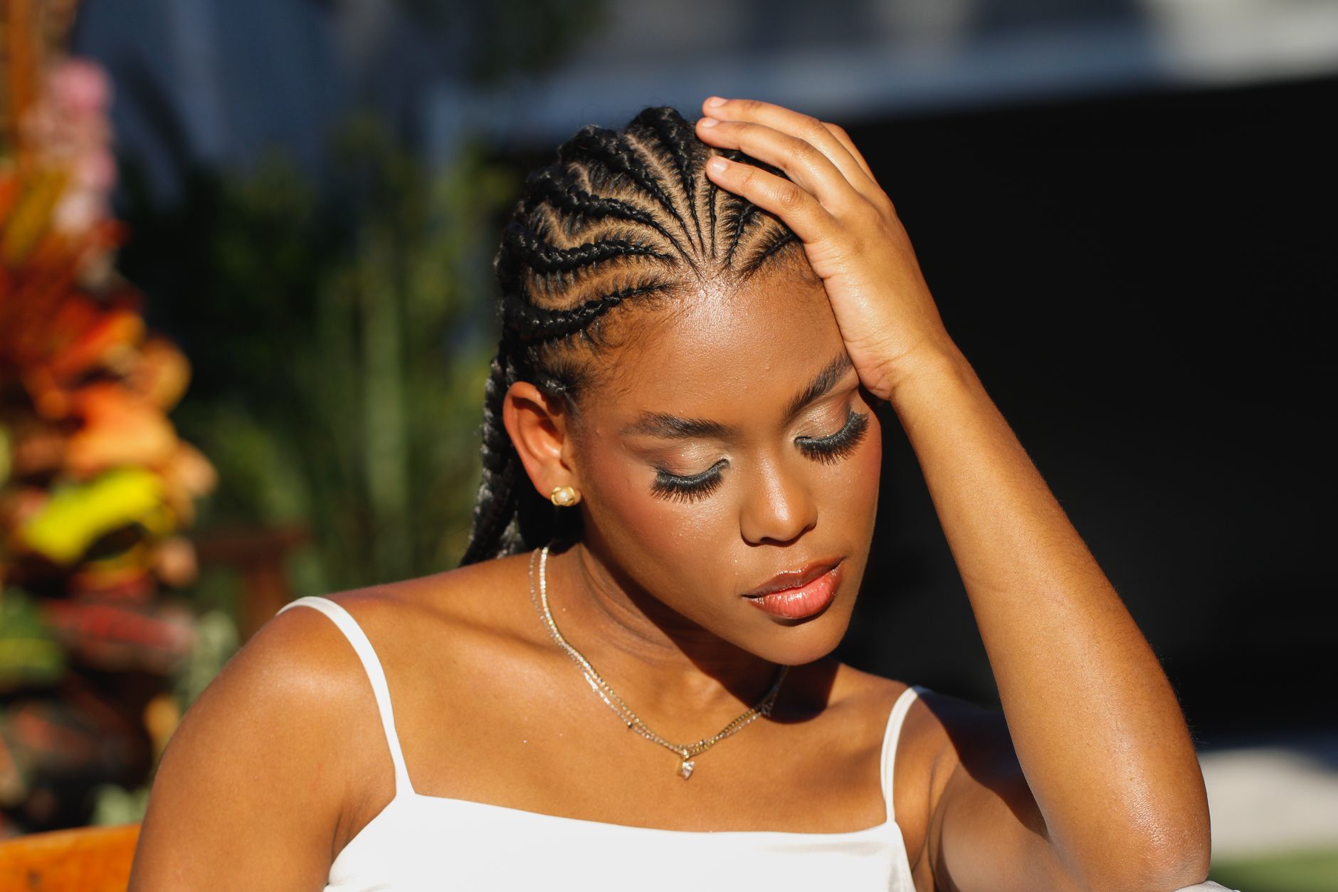 lady sitting in the sun wearing a white top and beautiful braids